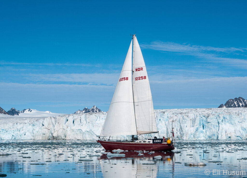 Sailing yacht S/V Anna II navigating Arctic sea ice in front of Lilliehöök Glacier, Svalbard, high-latitude cruising Norway